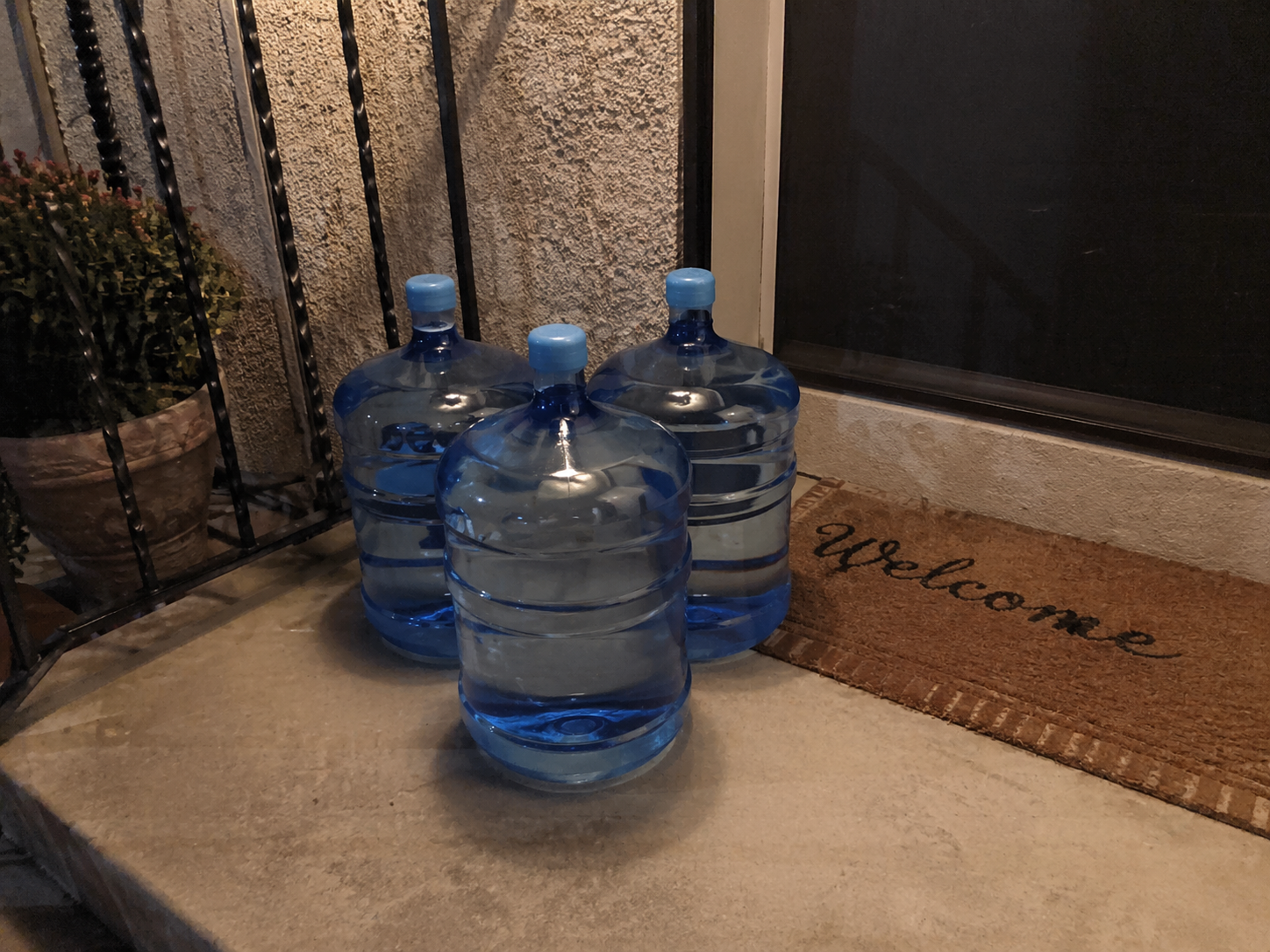 Water bottles placed neatly by a front door for delivery.